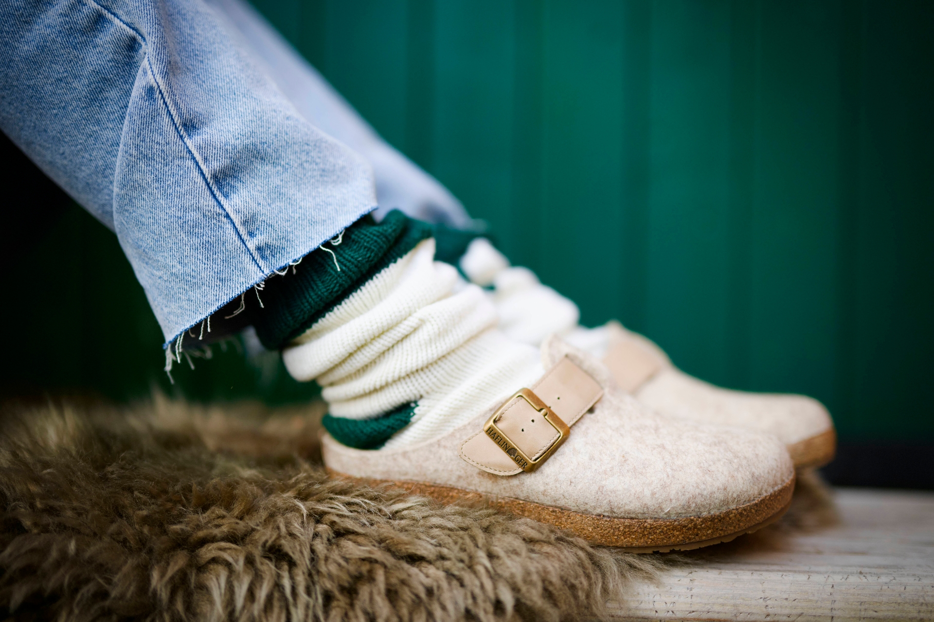 Woman lying her legs on a blanket, wearing thick scrunchy socks and beige slippers 