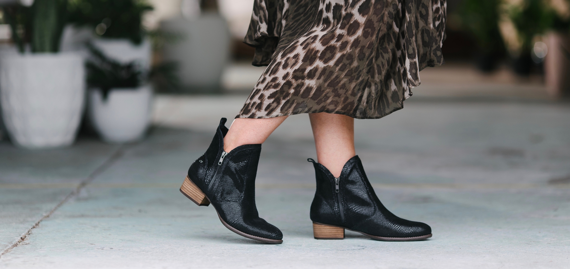 Woman in leopard print dress and lizard print shoes walking on sidewalk