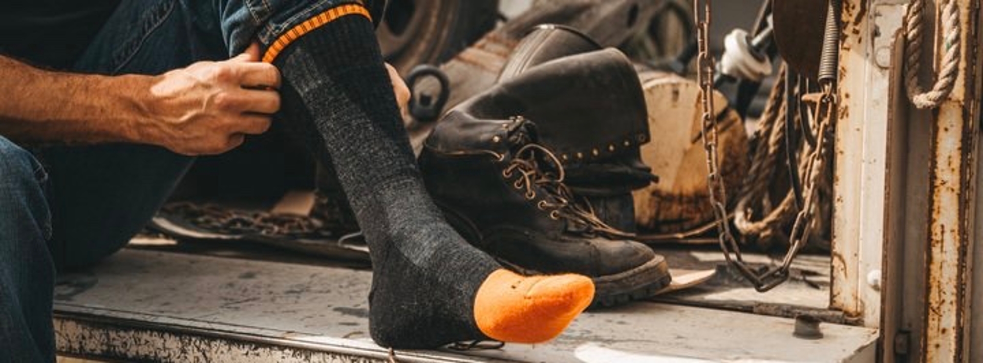 Worker pulling on knee-high socks, surrounded by logging materials