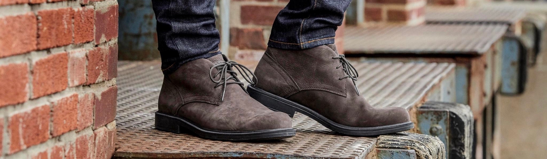 Feet in brown Dunham boots, standing on an elevated metal platform