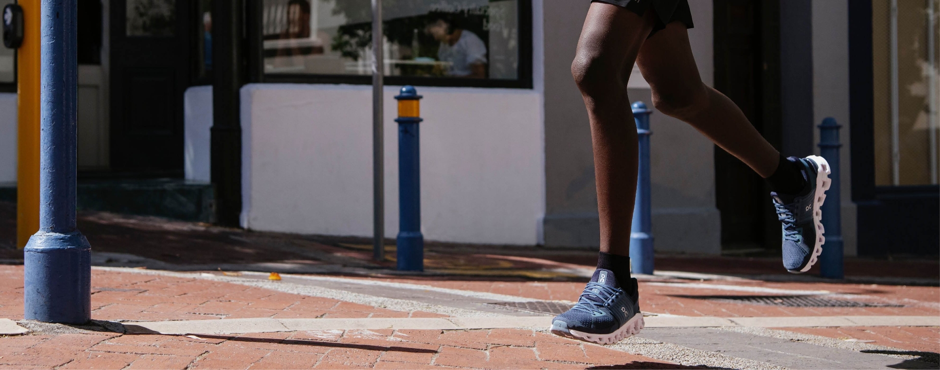up close shot of guy running wearing blue shoes on a brick sidewalk