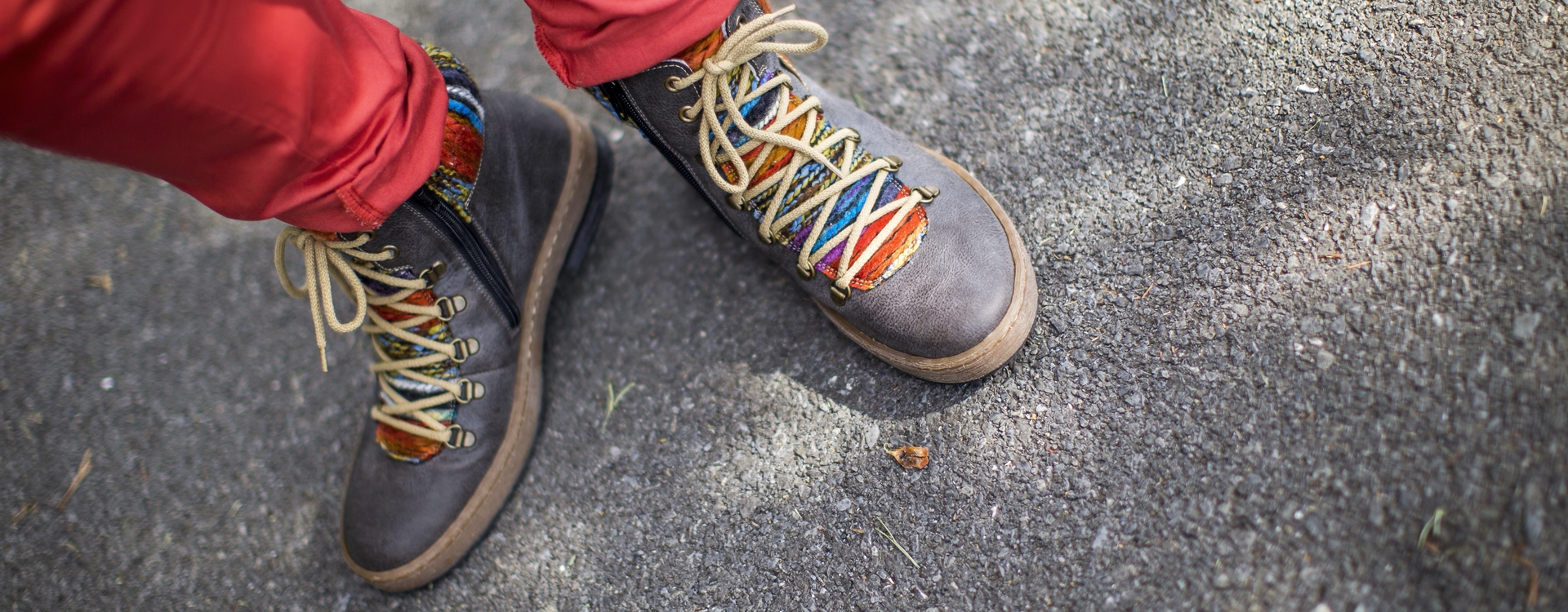 Legs in skinny red pants and sneakers standing on pavement